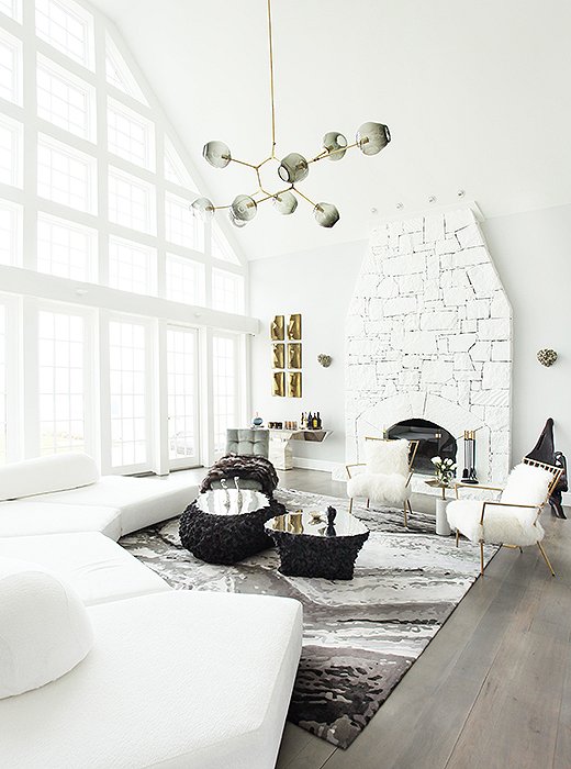 In the living room, a double-height ceiling and a wall of windows called for pieces with a bit of drama. An oversize Edward Fields rug printed to resemble a pebbled riverbed anchors coffee tables made of molten lava and a structured sectional. “Fur [real or faux] is an easy way to bring an element of nature into any room,” says Sasha, which is why she chose two chairs upholstered in Mongolian sheepskin and a silver-fox throw to drape over the Milo Baughman chaise. Find a similar throw (this one faux) here.
