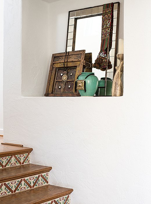 An artfully curated collection fills a nook above the tiled stairs.

