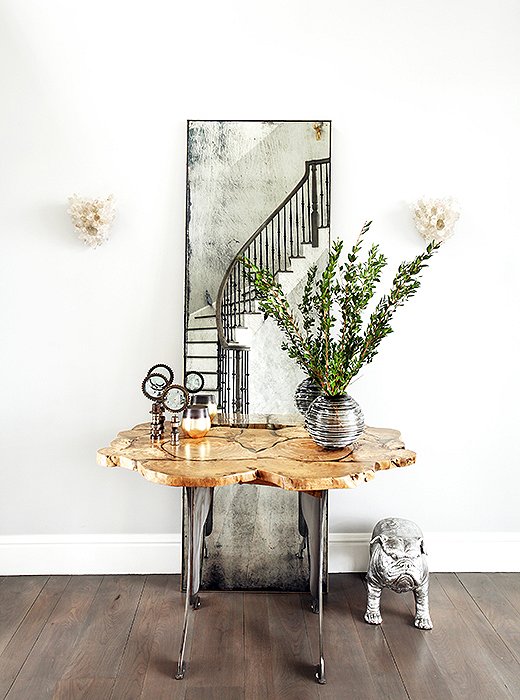 The foyer hosts a petite console table backed by a floor-length mirror constructed of antiqued glass. “The vignette has a bit of an Old World feel that works well in a countryside setting,” Sasha notes. Quartz sconces continue the glam theme while referencing the geology of the surrounding area. 
