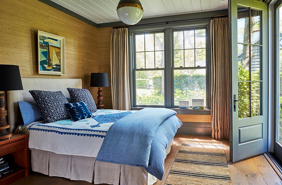 A painting from a flea market in Saint-Tropez crowns a linen-upholstered bed. Soft gray trim frames the seagrass-covered walls, while mismatched bedding in shades of indigo reflects the hues of Wooley Pond. Find the light fixture here.
