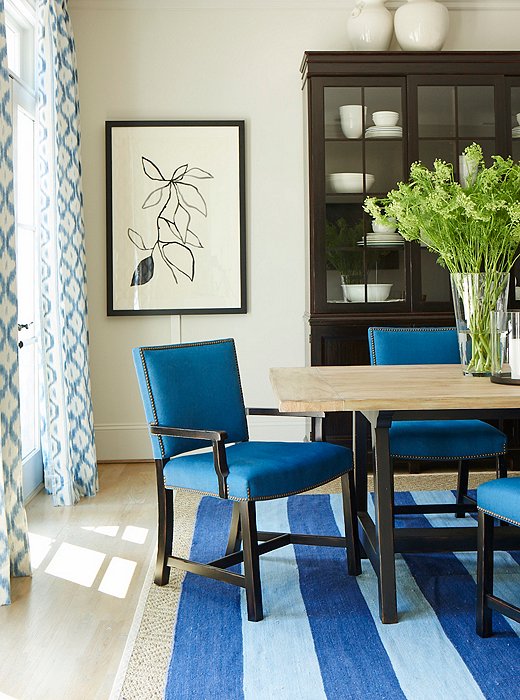 Touches of black add depth to a blue-and-white dining room, featuring pieces by Mark D. Sikes for Henredon.
