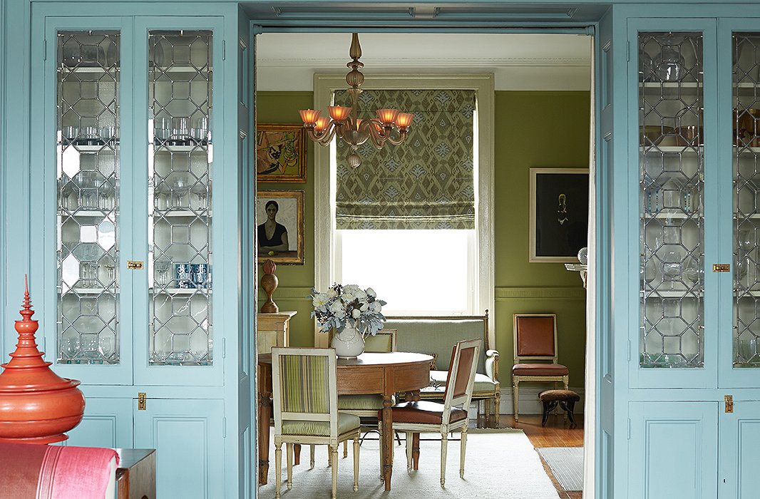 Blue-painted cabinets, which house glassware Sheila inherited from her parents and grandparents, divide the living room from the dining room. Sheila calls the dining room’s color a “Granny Smith apple green.” Find similar dining chairs here.
