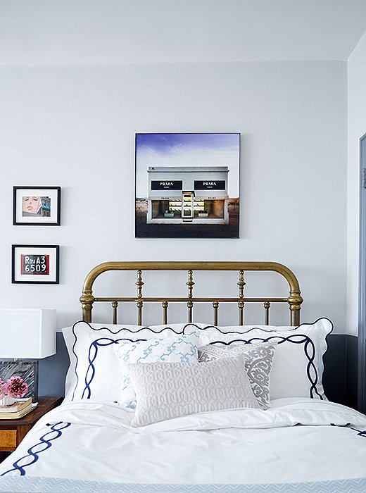The vintage brass bed has an alluring aged patina. It’s offset by navy-embroidered Matouk sheets, a photo by Gray Malin, and small-scale art.
