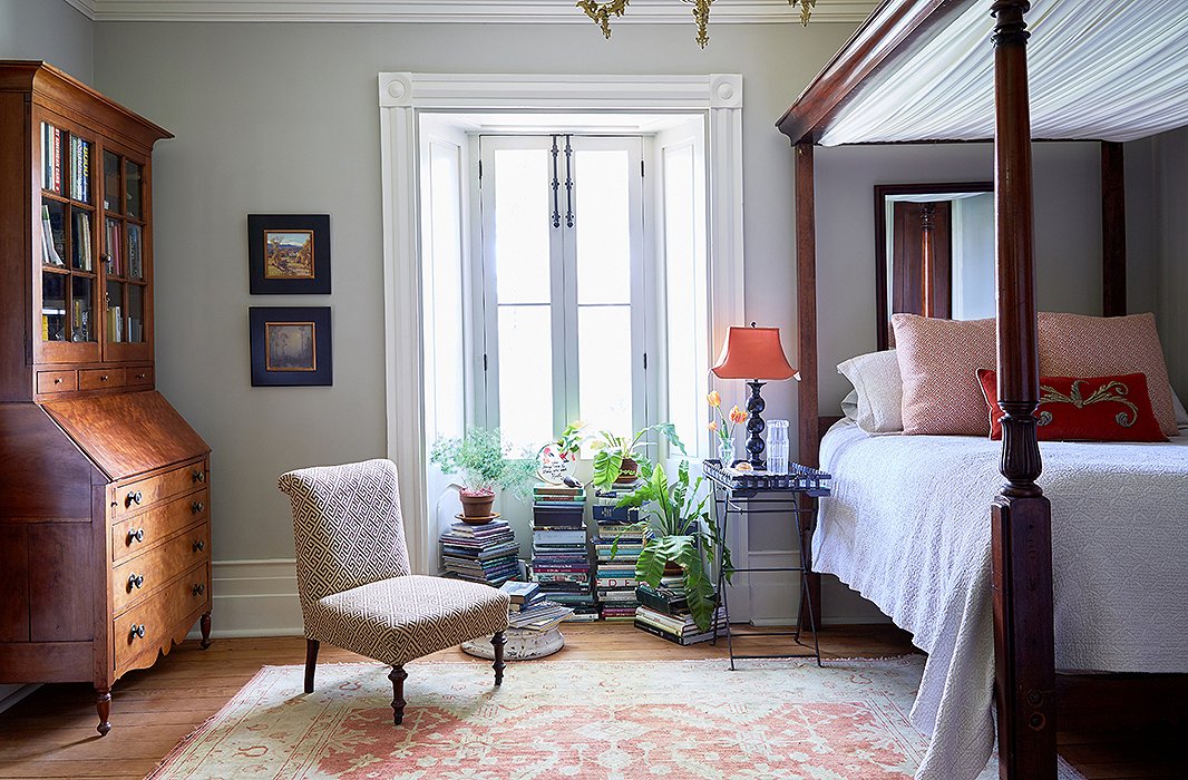 In the corner of the master bedroom, a secretary desk lends a sense of symmetry opposite the refurbished canopy bed.
