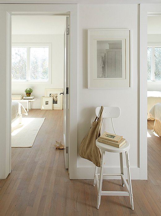 A steel stool sits beneath a still life matted and framed in two tones of white. Foley had the floors refinished to feel “modern and warm.”
