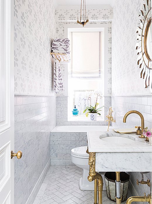 Designer CeCe Barfield livened up this petite bath with wallpaper custom-colored to match the tones of the marble tile. The resulting monochromatic look helps the space feel more expansive. Photo by Lesley Unruh.
