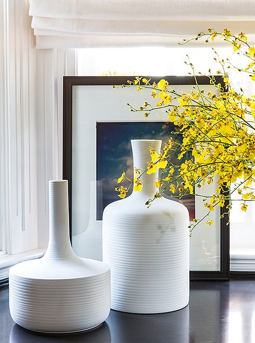 Don’t limit beautiful objects to the rest of the house—putting eye-catching pieces, like these glowing white vases, in the office helps make it a place you actually want to spend time in. 

