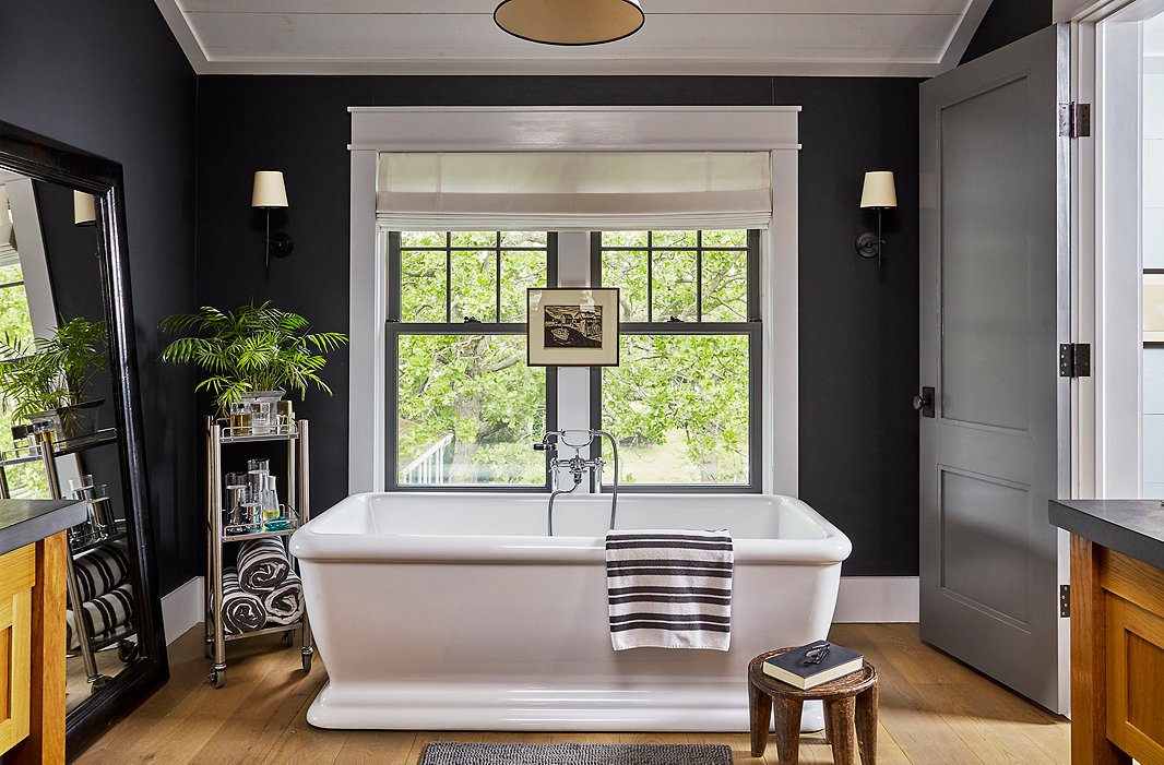 Deep-charcoal walls and crisp white trim add drama to the master bath. A pen-and-ink drawing from an antiques store in Milwaukee creates a focal point above the luxurious tub. 
