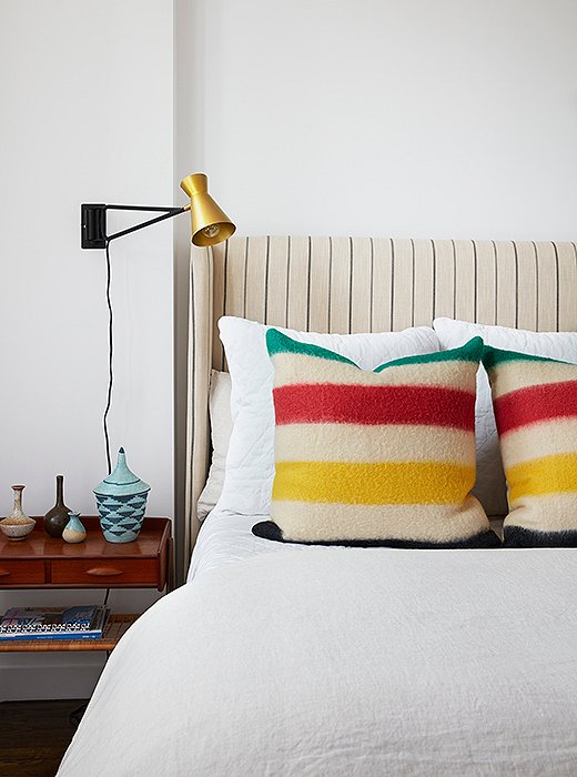 A guest-room bed serves as an experiment in scale. The bold primary stripes of the pillows work with the headboard’s fine lines to create maximum visual interest. “It’s a poppy room,” notes Sally, “and I think it represents the side of her that’s more laid-back. Everything here was about comfort, color, and texture.” 
