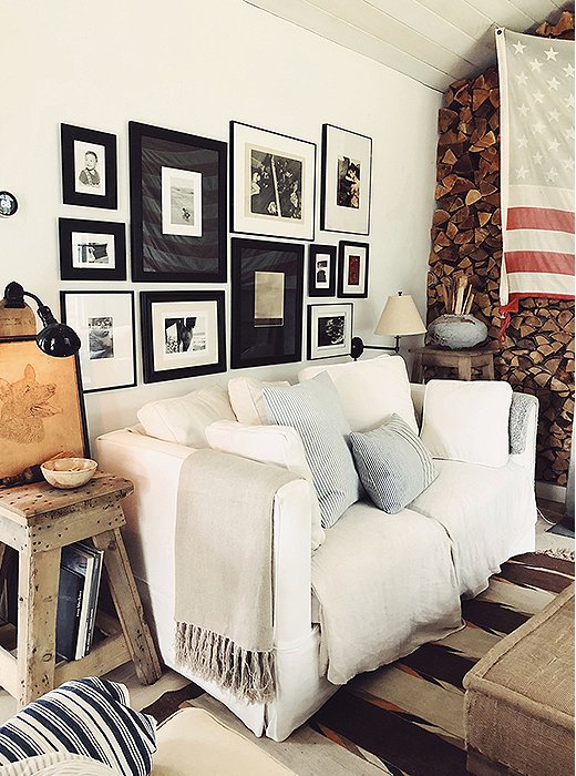 A wall of stacked logs, a sawhorse turned side table, a sun-faded flag: Collected antiques and weathered finishes lend laid-back Americana flair to the living room. Find a similar slipcovered sofa here.
