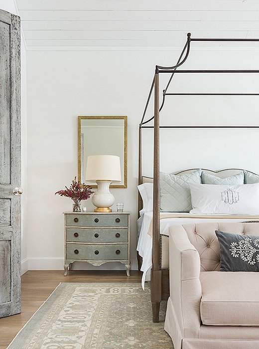 A beautifully distressed door leads to the master bedroom, where a graceful canopy bed makes the most of the soaring ceiling. Photo by Julie Soefer.
