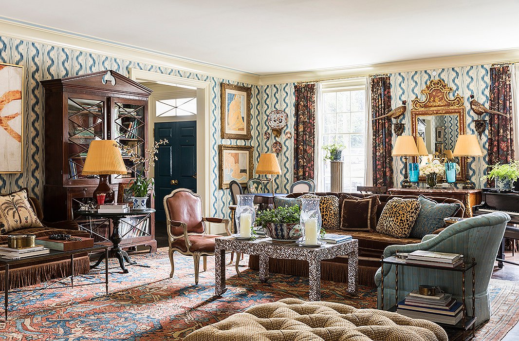 In the salon-style living room, sofas in Prelle silk velvet define the main seating areas. Patterns varying in scale but similar in tone (see the ivory-and-blue Pierre Frey wall covering, leopard-print pillows, and perfectly worn antique rug) were carefully chosen to complement, not clash. 
