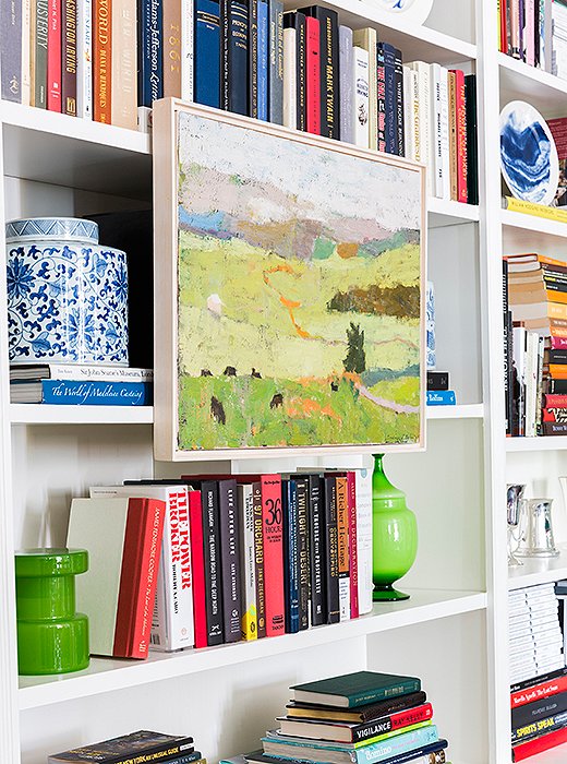 Bookshelves fill one wall of the living room, providing a home for CeCe’s collections of Italian midcentury glass and blue-and-white ceramics, along with her treasured library of decorating reference books. “It’s hard because there’s not endless amounts of room, so we try to just keep books that we love and use,” CeCe says. A painting that recalls the Virginia landscape (a gift from CeCe for her husband’s birthday) creates a colorful focal point.
