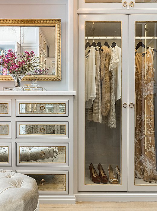 A mix of clear glass and antiqued mirror gives the master closet a glamorous feel (while keeping clutter hidden away). Photo by Julie Soefer.
