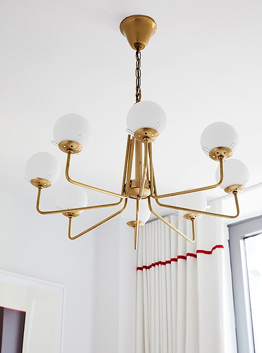 No room is too small for a statement fixture. “It creates height,” says Sally. “There was very little you could do in here other than floor-length window treatments and a chandelier to create a sense of grandeur.”  
 
