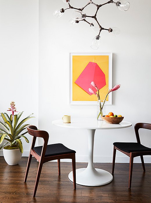 More midcentury in the kitchen. A white Tulip table and two Scandinavian-style chairs float beneath a chandelier of bronze and wineglass-cupped bulbs. The art? “Yellow and pink are colors Mindy really wanted to use,” says Sally, “but we couldn’t really find the right moment for it. So during the 11th hour, we found this piece and installed it without ever showing it to her.” Needless to say, she was pleased. 
