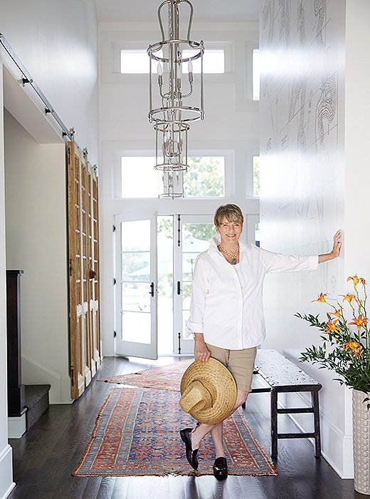 Barbara didn’t feel that the house’s layout lent itself to an overly formal entryway, but she created a nice welcoming moment here, pairing several of her own tiered pendant fixtures with natural woods and casually overlapping carpets. “Those are my husband’s family’s rugs. They’re pretty thin and pretty worn, and I love them that way,” she says.
