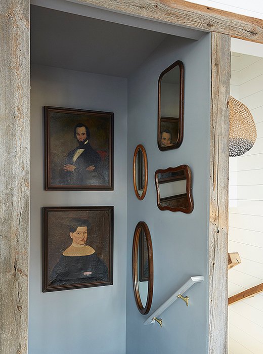A stairway leading to the kitchen is accented with vintage artwork and mirrors. The portrait at bottom left was repaired with a Band-Aid—a cheeky solve that turns a traditional touch into a contemporary showstopper.
