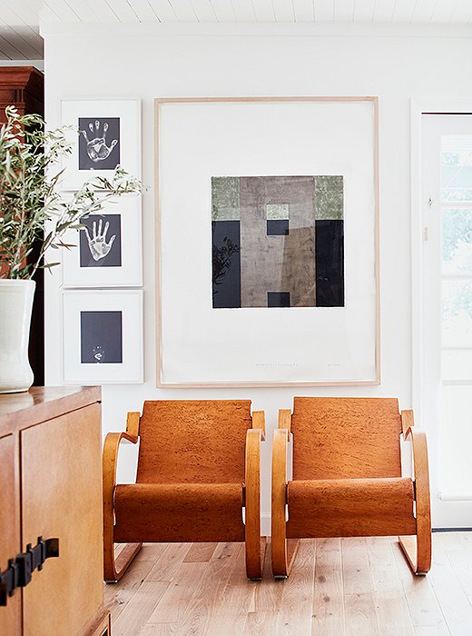 Jon Groom’s Evidence of Monk #2 hangs above a pair of Alvar Aalto armchairs, creating a visual divide between the living room and the dining area. The three hands, photographed by Gary Schneider, are those of Laura, Cloud, and their daughter, Tess, when she was born.  
