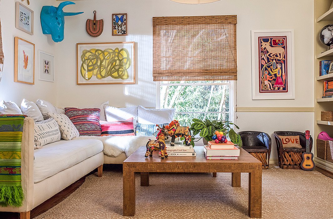 Colorful art and a layer of patterned pillows brighten up the playroom’s neutral foundation. 
