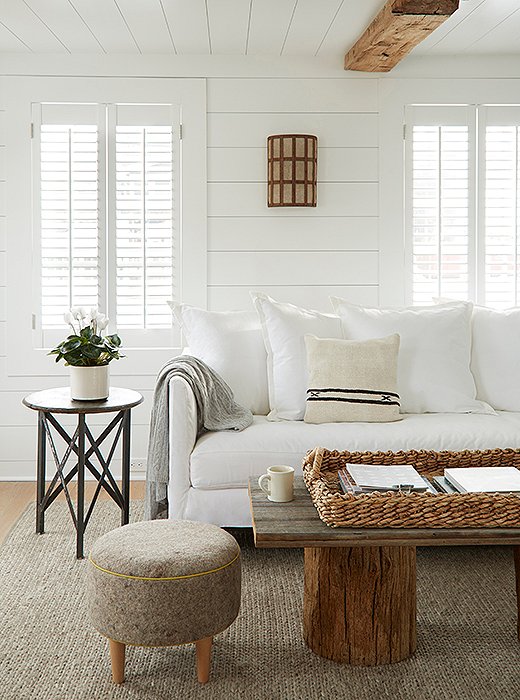 In the Webster room, a sofa slipcovered in white canvas rests on a braided wool rug. A custom coffee table anchors the cozy lounge spot.
