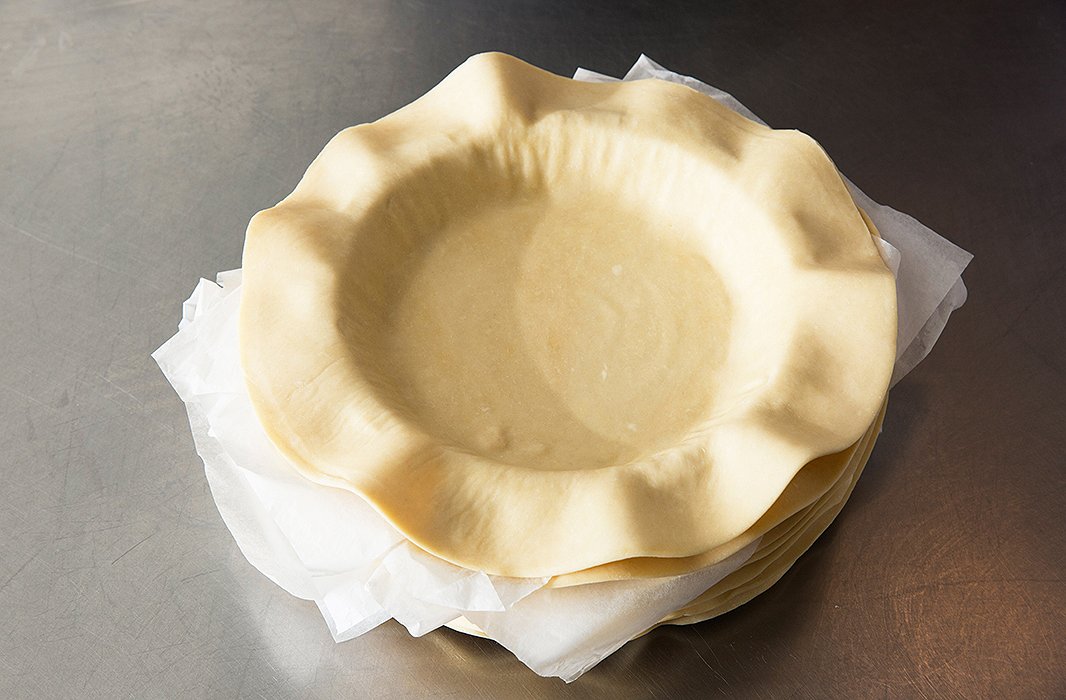 A stack of crusts, each rolled, placed, and trimmed on the pie pan.
