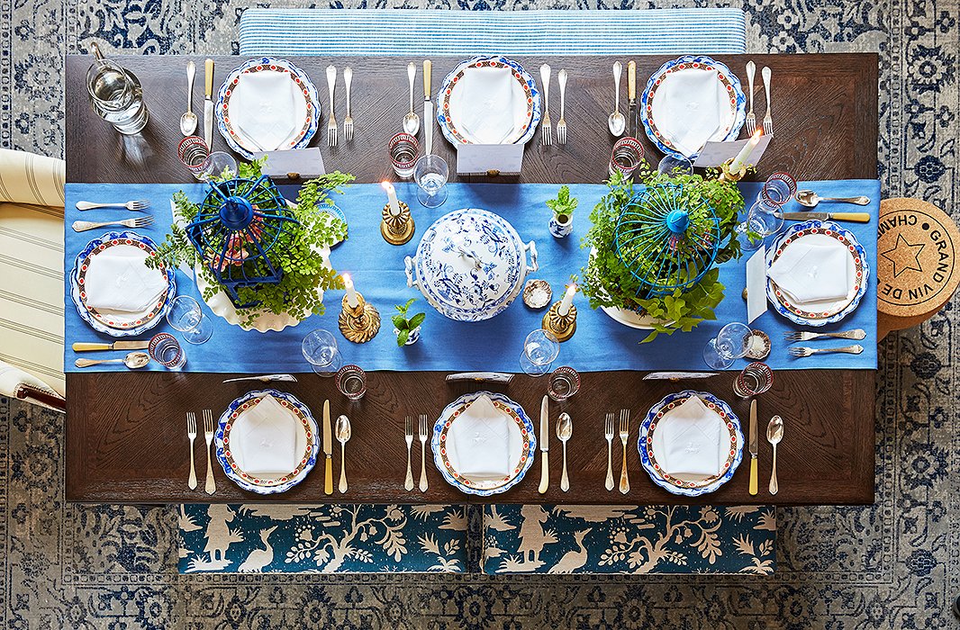 The extendable dining table serves as the focal point of the multitasking space: By day it’s a desk, and by night it’s a table for a crowd. Stephanie’s existing armchair, striped bench, and cork stool were a perfect match for the new dusty blue rug and benches upholstered in an oversize chinoiserie print. Featuring a medley of vintage plates, French flatware, and brass accents, the tablescape showcases Stephanie’s love of blue and white—and her penchant for mixing old and new. 
