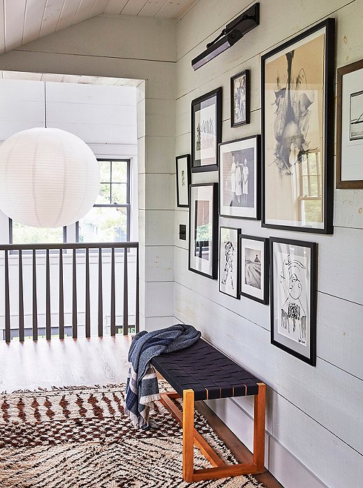 The upstairs gallery wall features a collection of black-and-white works, many of them gifts. A vintage Beni Ourain rug adds tonal texture.

