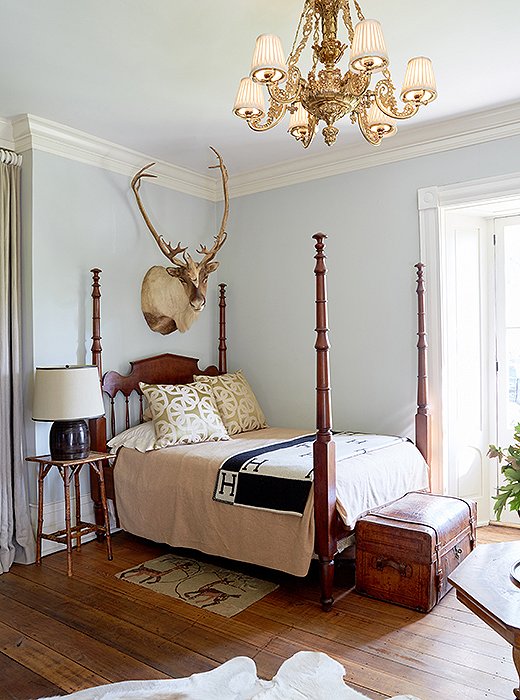 In the guest room, a four-poster bed footed by a leather trunk is made to feel fresh with the addition of a black-and-white Hermès throw. 
