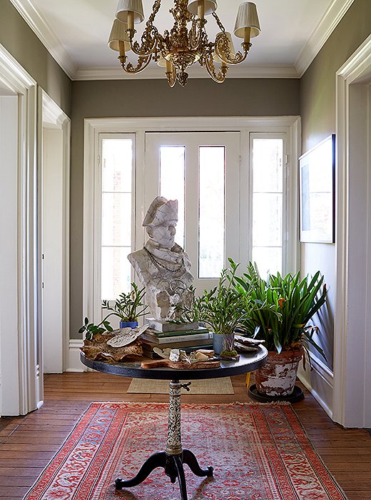 A bust of Napoleon rests on a table found in Nashville. Around its neck hang beads and a Mercedes-Benz medallion, creating a moment of humor in the pass-through space. 
