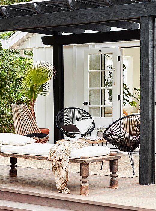 Outside, a black pergola shades a Nepali daybed and folding chair from the ‘60s. 
