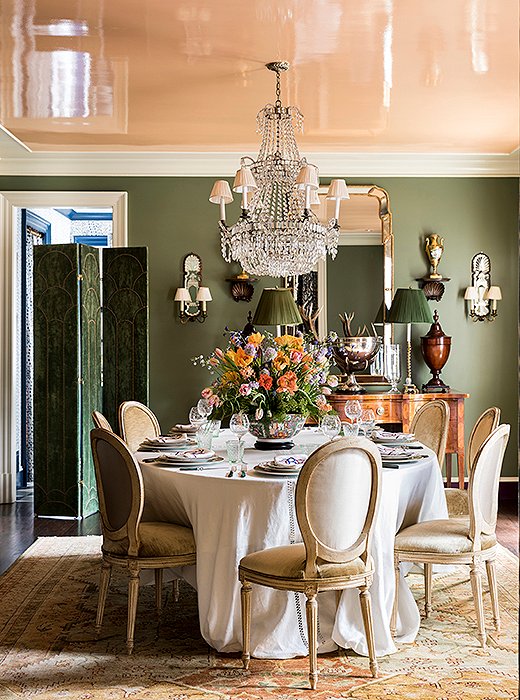 Louis XVI chairs dressed in velvet encircle a table crowned by an antique chandelier. The combination of the apricot-lacquered ceiling and the dusty green walls creates a flattering glow. “In the evening, the light that’s reflected is just magic,” Danielle says. “It’s like liquid candlelight.” 
