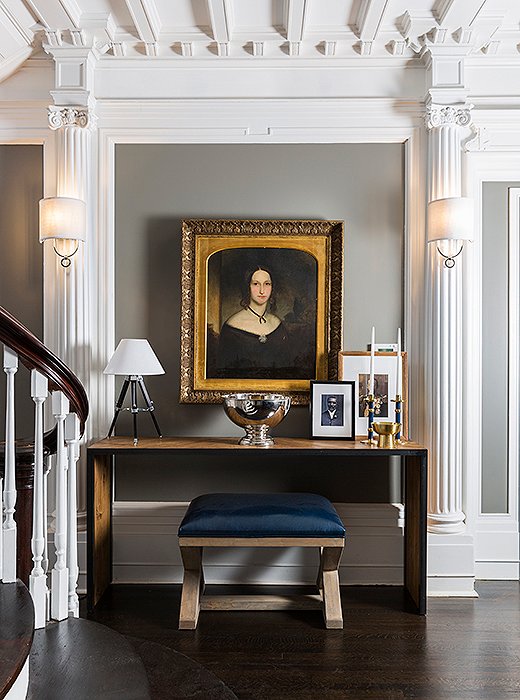 An oil portrait in a gilded frame hangs above a contemporary console by CFC accented with a surveyor-style lamp by Ralph Lauren Home. 
