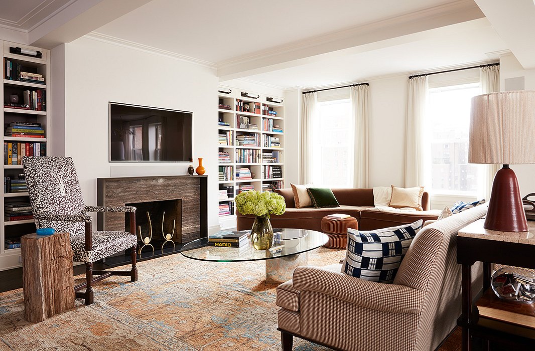 A neutral rug unifies a houndstooth sofa and a patterned armchair, while a glass coffee table offers a modern touch.
