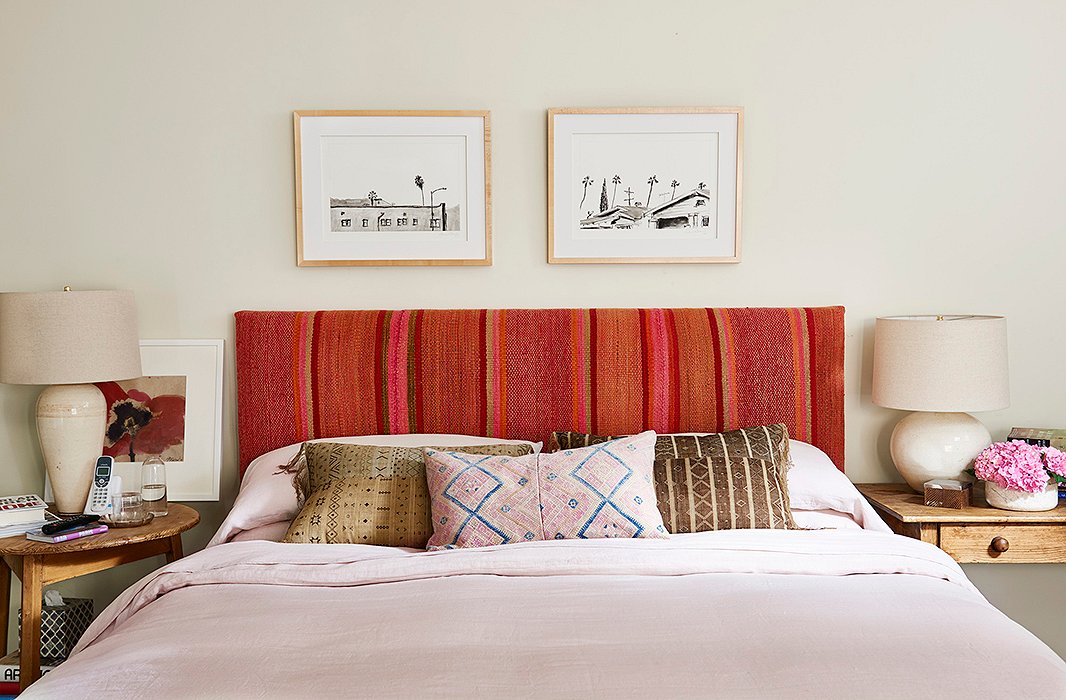 Pink comes into play yet again on the bedroom’s headboard, crowned with a pair of black-and-white prints and made pleasantly imperfect with mismatched bedside lamps. 