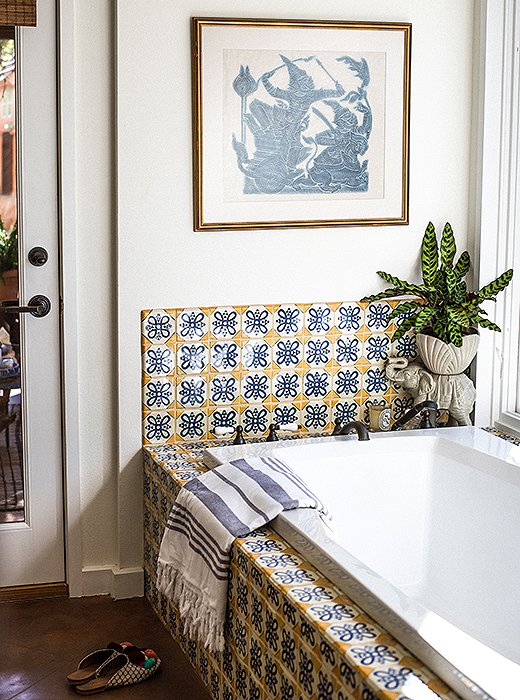 A potted plant, a Turkish towel, and a vintage artwork turn the master bath into a welcoming oasis.

