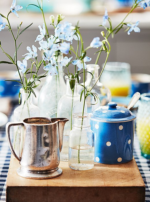 A rustic wooden cutting board elevates a medley of vintage tableware to centerpiece status.
