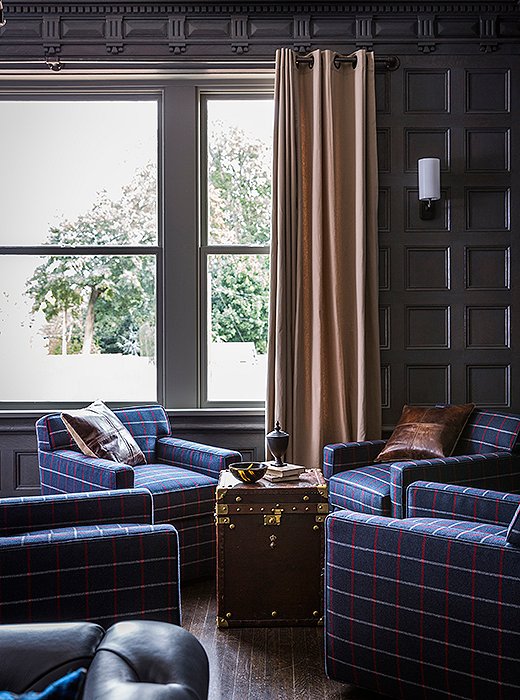  A set of plaid Joe Ruggiero club chairs (topped with rich leather pillows) makes for a comfy seating area. The vintage trunk serves as a handsome cocktail table. 
