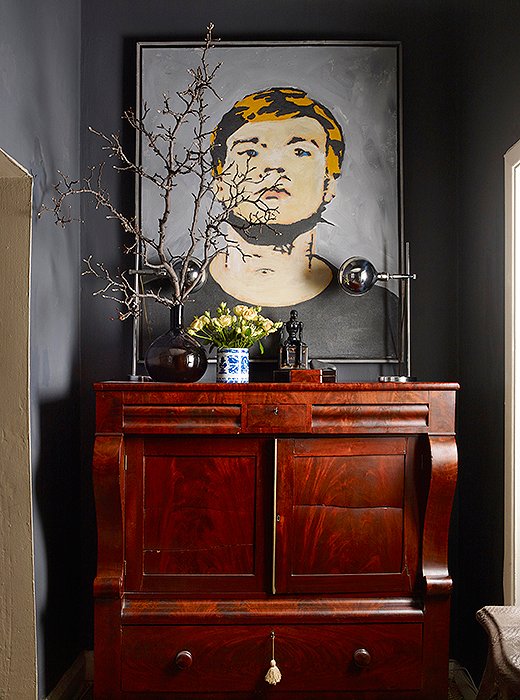 In the entry, a Warhol reproduction found on the corner of Fifth Avenue and 11th Street hangs against a wall painted Benjamin Moore’s French Beret. Below, a vintage American Empire cabinet hosts a pair of polished-nickel task lamps. 
