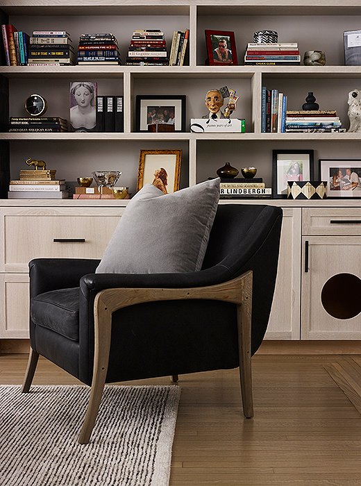 In the living room, a leather armchair features wood accents selected to complement the sofa, cabinetry, and floors. Behind, artfully arranged bookcases showcase Morgan and Suki’s extensive collection of coffee table books, photographs, and objets.
