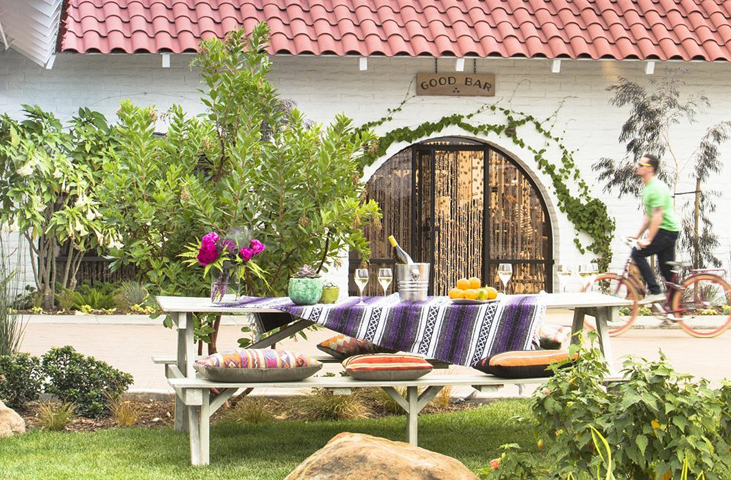 Make a picnic table a little more comfy with a pile of plush textiles. Photo courtesy of The Goodland.
