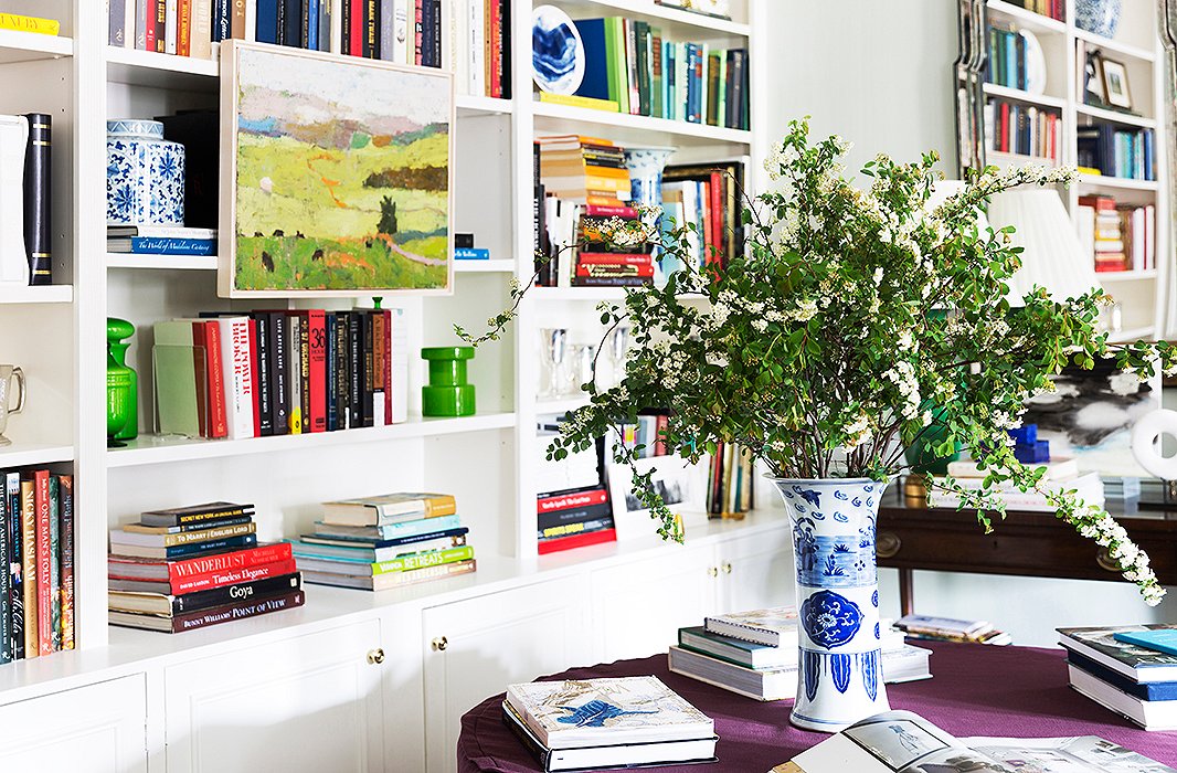 Built-in bookshelves in CeCe’s Manhattan apartment hold her treasured design library, along with a mix of modern blue-and-white plates, green Italian art glass, and traditional chinoiserie ceramics.
