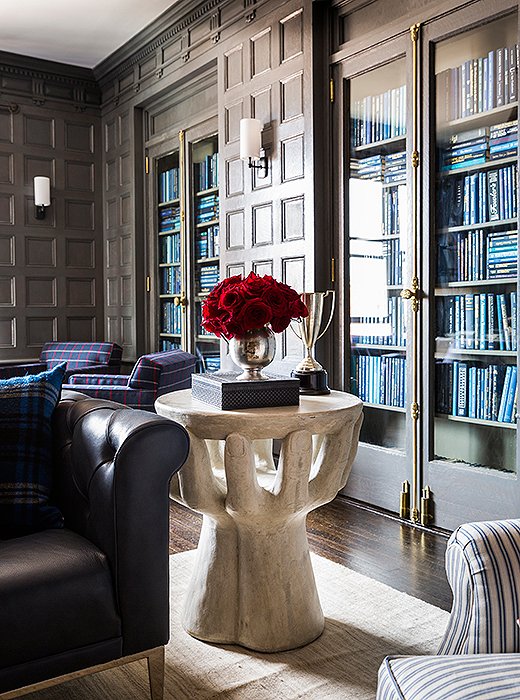 A sculptural resin side table adds height and heft beside a chesterfield sofa. On top, vintage trophies in pewter and silver lend the striking vignette a classic twist. 
