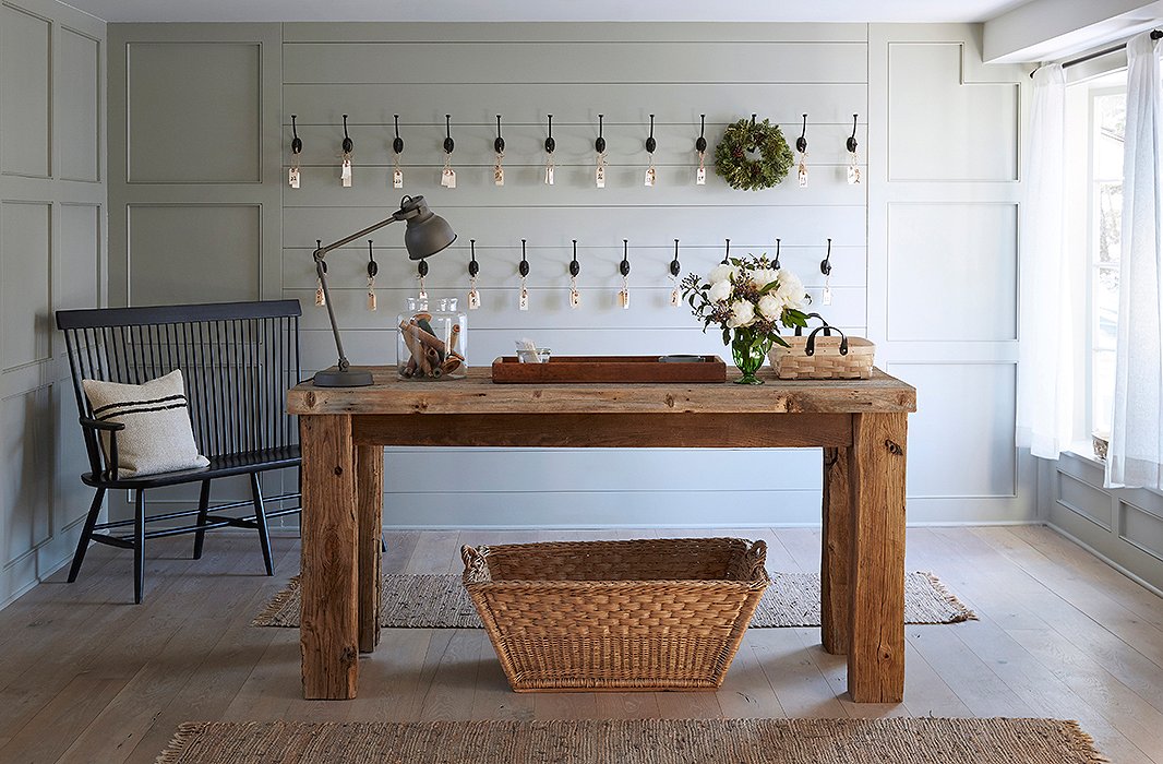 A farm table custom-made by local craftsmen acts as a welcome station. Behind, shiplap walls and a Windsor bench exemplify country chic.
