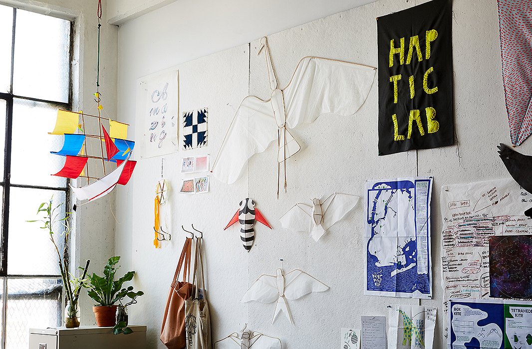A few of Haptic Lab’s popular kites, fashioned in the shapes of sailing ships and animals, hang alongside patterned fabric swatches and printed maps in the studio. 
