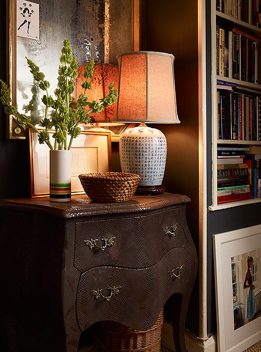 A bombé chest finished in faux lizard serves as a snazzy foundation to an otherwise traditional vignette. Details such as a nubby Empire lampshade and a woven basket turned catchall epitomize Michael’s penchant for rusticity. 
