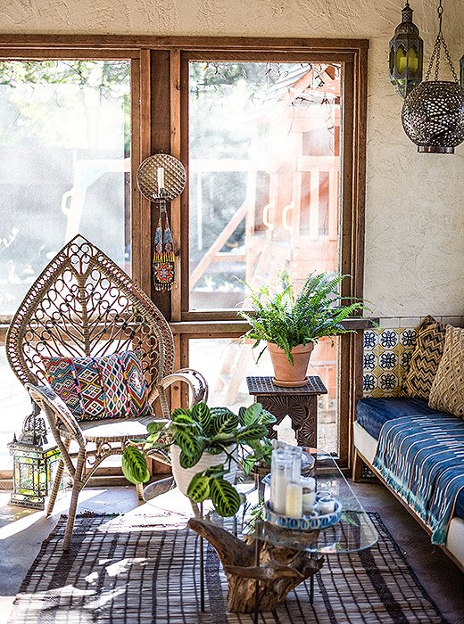 Moroccan-inspired lighting, a vintage tree-trunk table, a rattan chair, and a host of vintage textiles make for a delightfully laid-back sitting area. Photo by Shayna Fontana.
