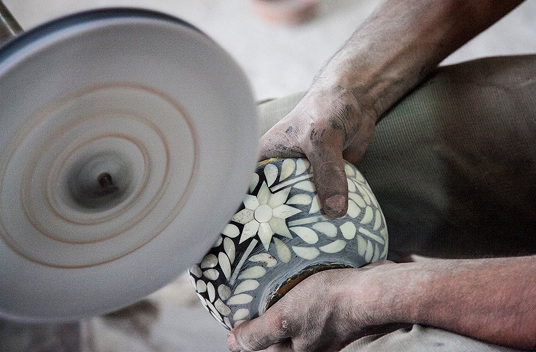 An artisan smooths the surface of a bone-inlay bowl. Photo courtesy of Mela Artisans.
