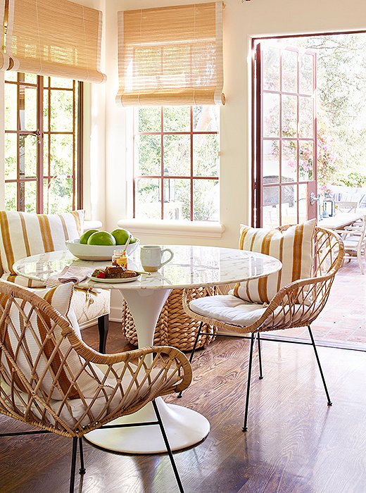  A touch of midcentury, courtesy of the marble-top Tulip table and rattan chairs, brings a sophisticated sense of boho style into the mix.
