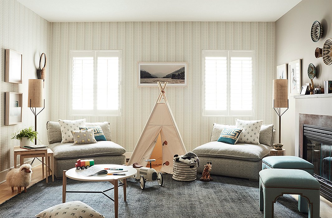 A tepee between windows encourages imaginative moments of play, while a low-lying table offers a surface for crafts and games. What appear as two oversize chairs serve double duty as a sofa; they can easily be pushed back together when the tepee is not in use.
